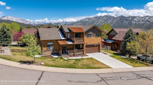 rustic home with a balcony, an attached garage, a front yard, driveway, and a mountain view