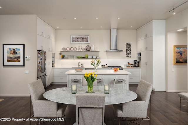 102 Evans Rd Unit 104, Basalt, CO 81621 - kitchen featuring wall chimney range hood, stainless steel appliances, an island with sink, light countertops, and dark wood-style floors