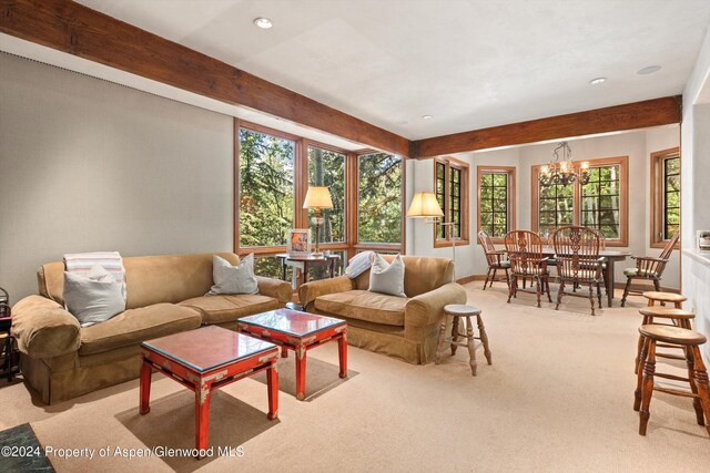 carpeted living room with beam ceiling and an inviting chandelier