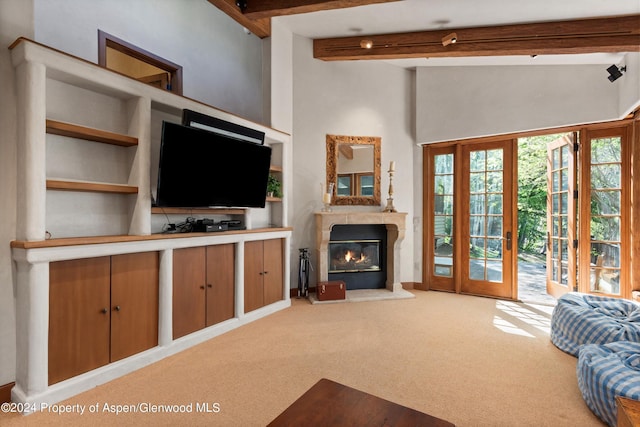 living room featuring carpet flooring, built in shelves, beamed ceiling, and french doors