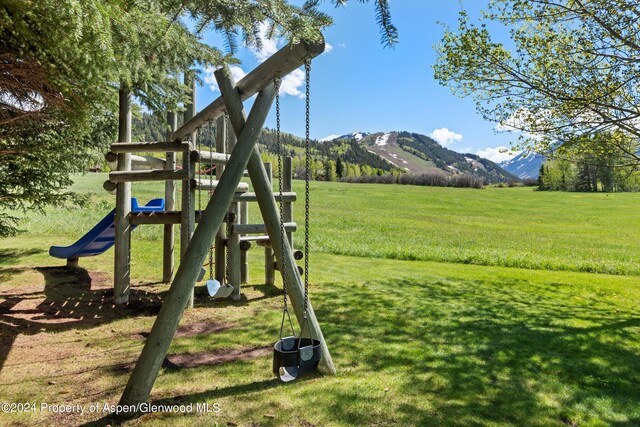 view of play area featuring a mountain view and a yard