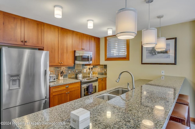 kitchen with a breakfast bar, light stone countertops, sink, and stainless steel appliances