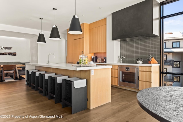 kitchen featuring decorative backsplash, modern cabinets, light countertops, and wood finished floors