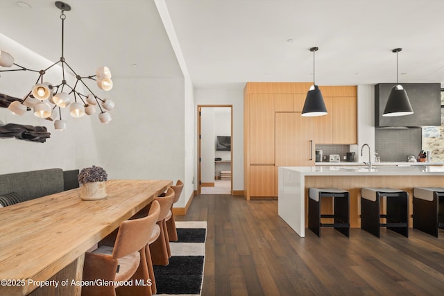 kitchen with light brown cabinetry, light countertops, a kitchen breakfast bar, dark wood-style floors, and modern cabinets