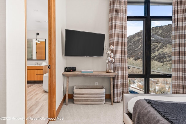 bedroom with carpet floors, connected bathroom, baseboards, and a sink