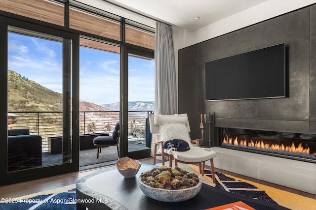 sitting room featuring a glass covered fireplace, a wall of windows, and wood finished floors