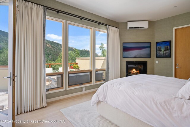 250 Mountain Laurel Dr Unit B, Aspen, CO 81611 - bedroom featuring a wall unit AC, a large fireplace, and wood finished floors