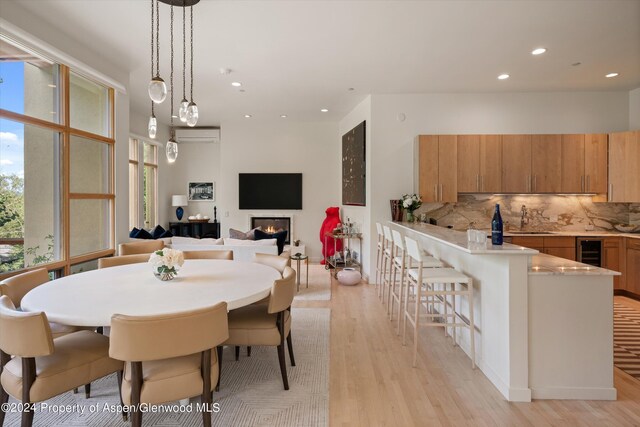 250 Mountain Laurel Dr Unit B, Aspen, CO 81611 - dining area featuring light wood-style floors, a glass covered fireplace, recessed lighting, beverage cooler, and an AC wall unit