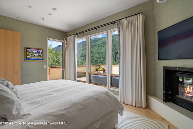 250 Mountain Laurel Dr Unit B, Aspen, CO 81611 - bedroom featuring access to exterior, wood finished floors, a glass covered fireplace, and wallpapered walls