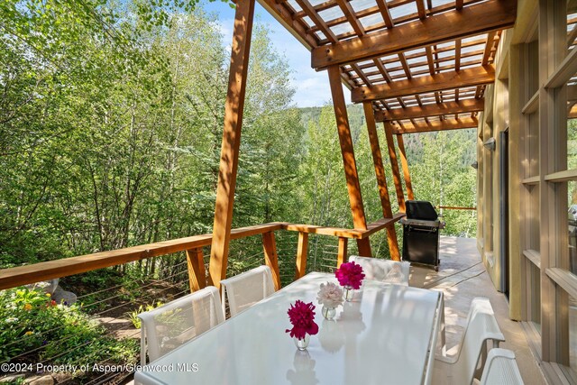 250 Mountain Laurel Dr Unit B, Aspen, CO 81611 - deck featuring a pergola, outdoor dining space, area for grilling, and a view of trees