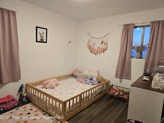 bedroom featuring dark hardwood / wood-style flooring and a nursery area