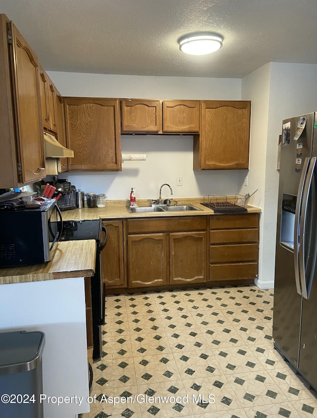 kitchen with sink, stove, a textured ceiling, and fridge with ice dispenser