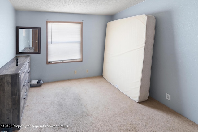 unfurnished bedroom featuring light carpet and a textured ceiling