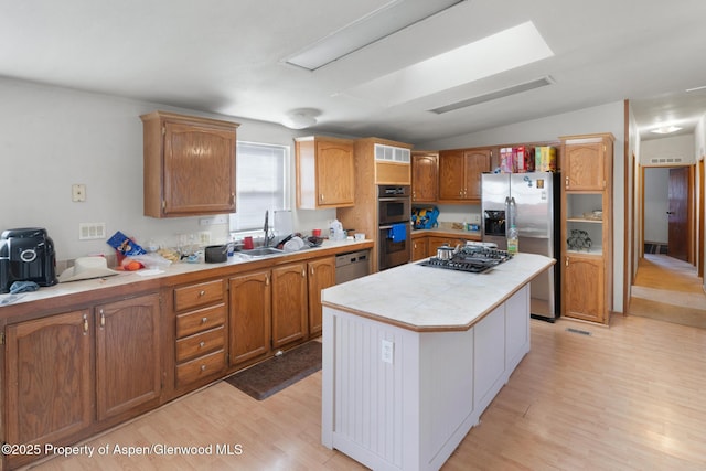 kitchen featuring lofted ceiling, sink, appliances with stainless steel finishes, a center island, and light hardwood / wood-style floors