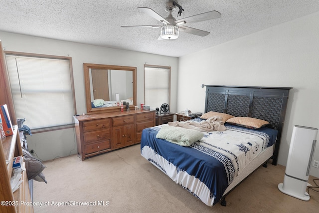 carpeted bedroom featuring ceiling fan and a textured ceiling