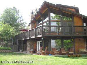 rear view of house with a wooden deck, a chimney, and a yard