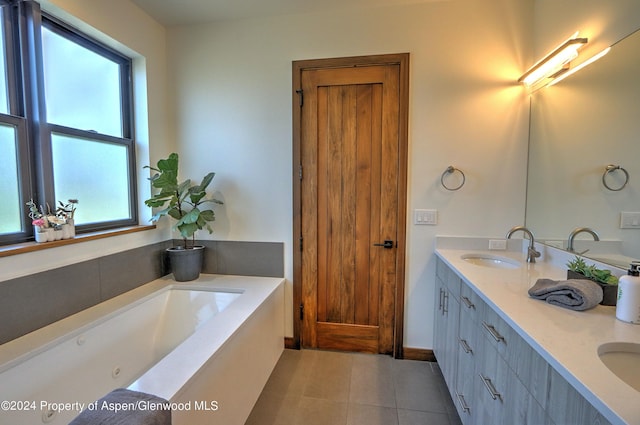 bathroom with a washtub, vanity, a healthy amount of sunlight, and tile patterned flooring