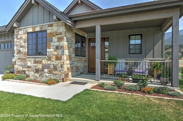 view of exterior entry with a lawn and covered porch