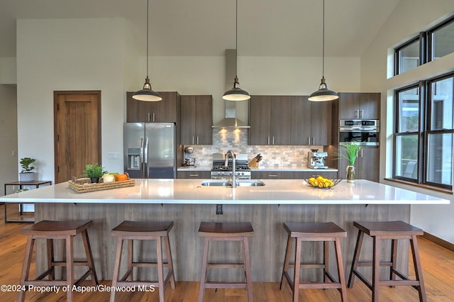 kitchen with dark brown cabinetry, sink, an island with sink, and stainless steel appliances