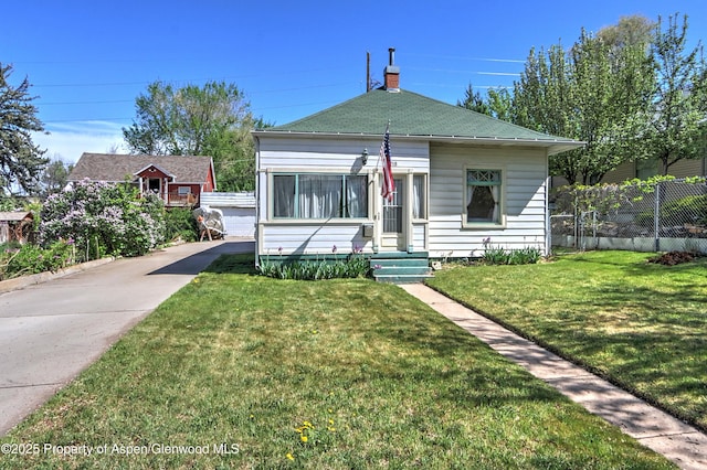 bungalow-style house with a chimney, fence, an outdoor structure, a front yard, and roof with shingles