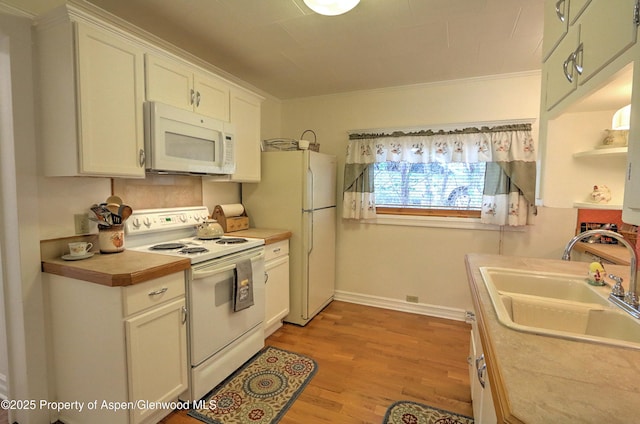 kitchen with white appliances, a sink, light wood-style floors, light countertops, and white cabinets