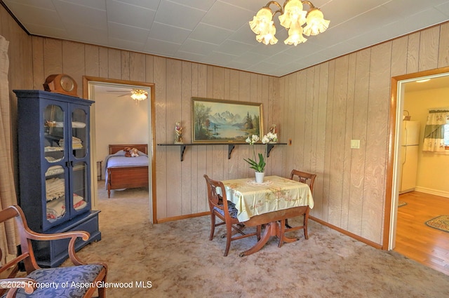 dining room featuring wood walls, a notable chandelier, and baseboards