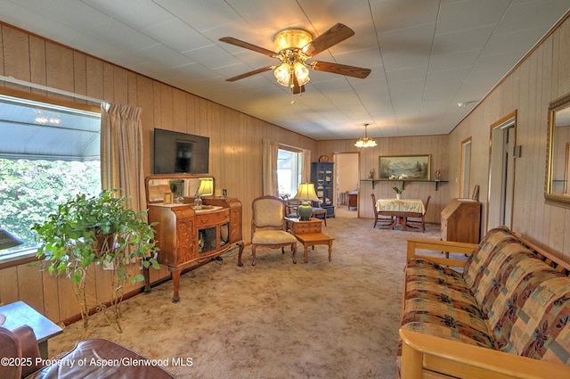 living room featuring carpet, wooden walls, and a ceiling fan