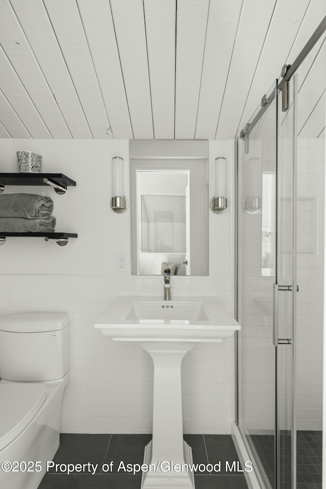 bathroom with an enclosed shower, tile walls, and toilet