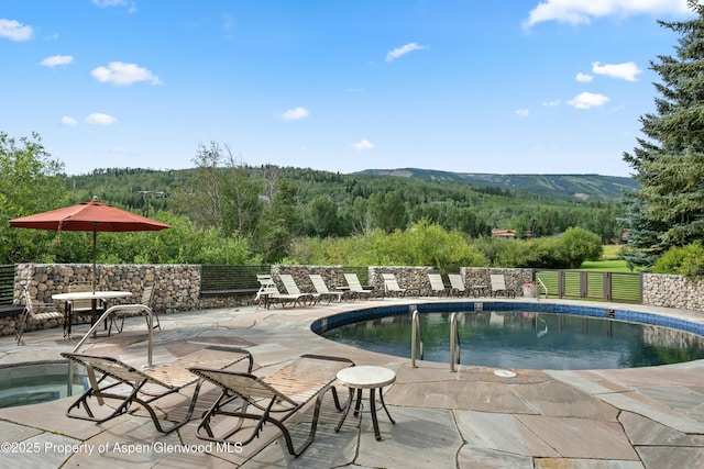 view of pool with an in ground hot tub, a mountain view, and a patio area