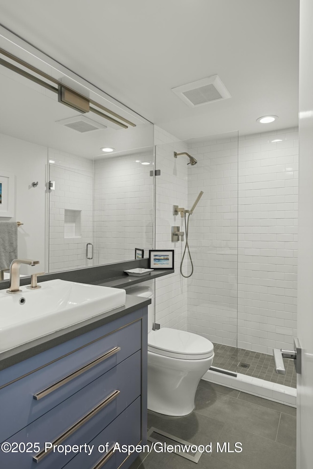 bathroom with tile patterned floors, vanity, toilet, and a shower with shower door