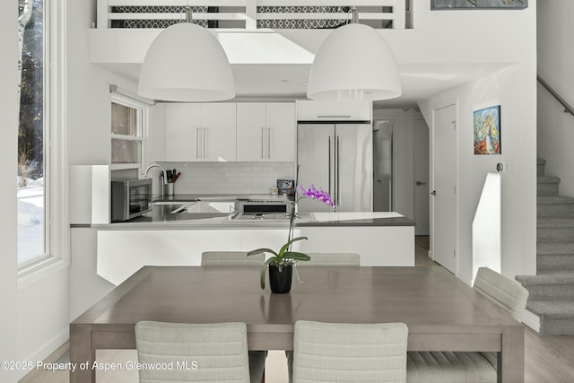 kitchen with sink, white cabinetry, decorative light fixtures, a kitchen breakfast bar, and stainless steel appliances