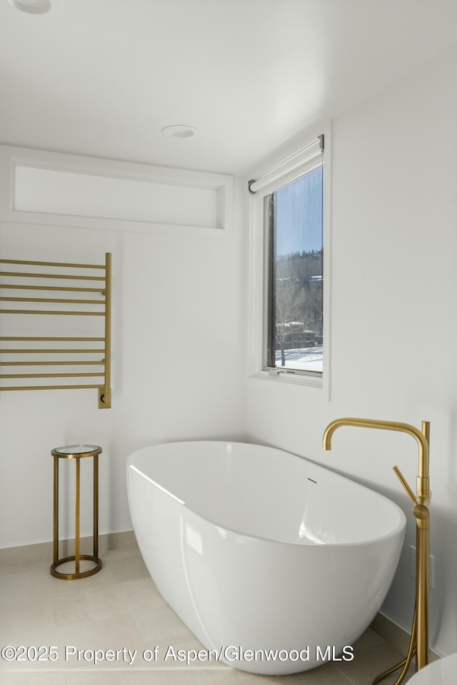 bathroom with tile patterned flooring, a bathtub, and radiator heating unit