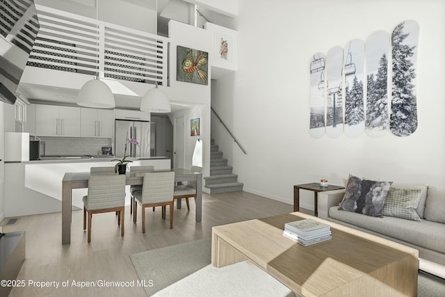 living room with a towering ceiling and light wood-type flooring