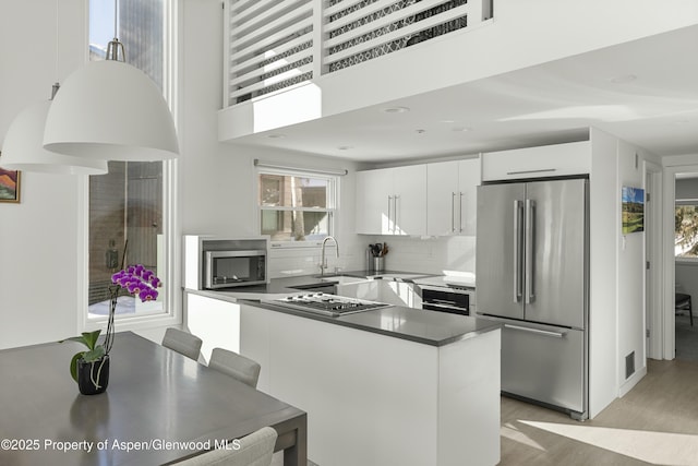 kitchen featuring sink, appliances with stainless steel finishes, white cabinetry, tasteful backsplash, and light wood-type flooring