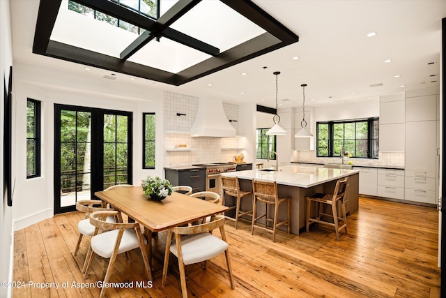 dining area with light hardwood / wood-style flooring, french doors, and sink