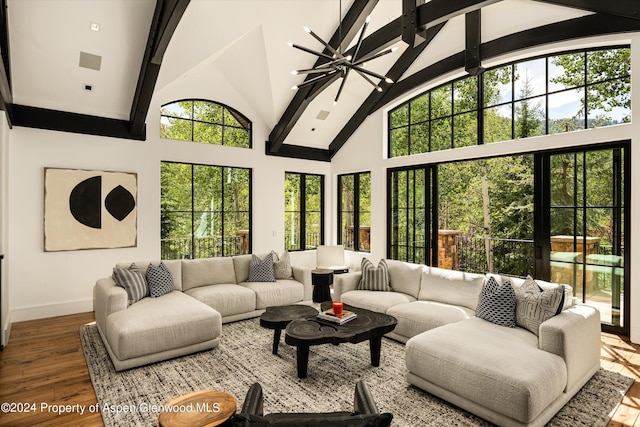 living room with hardwood / wood-style floors, a towering ceiling, and an inviting chandelier