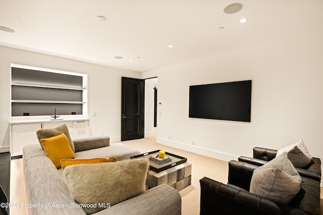 living room with built in shelves, light colored carpet, and sink