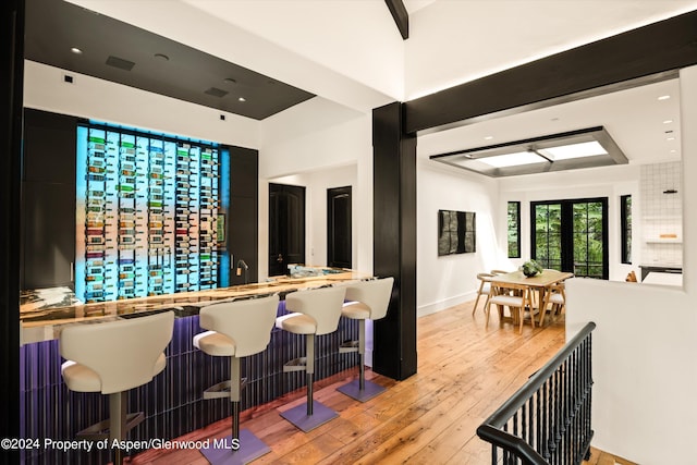 bar with beamed ceiling and light hardwood / wood-style flooring