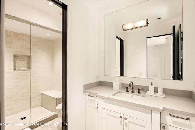 bathroom featuring vanity, toilet, and tiled shower