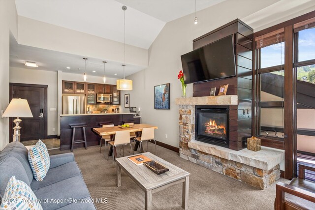 living room featuring a fireplace, carpet floors, and vaulted ceiling