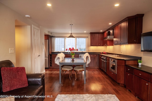 kitchen with appliances with stainless steel finishes, pendant lighting, and dark hardwood / wood-style flooring