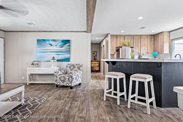 kitchen with visible vents, wood finished floors, freestanding refrigerator, and a kitchen breakfast bar