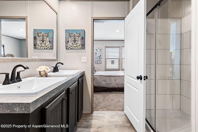 bathroom with connected bathroom, wood finished floors, a sink, and an enclosed shower