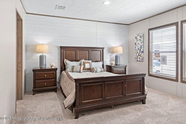 bedroom featuring crown molding, visible vents, a textured ceiling, and light colored carpet