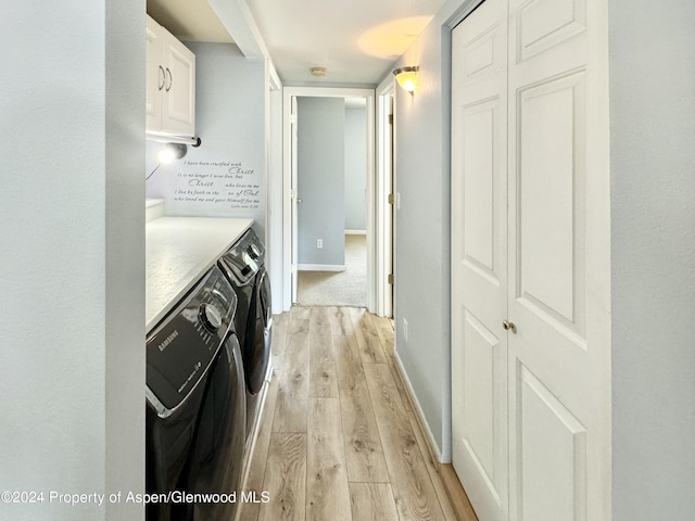 laundry area with cabinets, light hardwood / wood-style flooring, and washer and clothes dryer