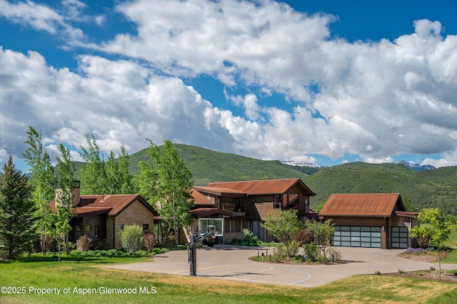 425 Aspen Valley Ranch Rd, Woody Creek, CO 81656 - view of front of home with stone siding, a mountain view, metal roof, a garage, and a chimney