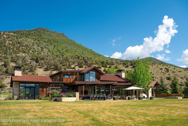 425 Aspen Valley Ranch Rd, Woody Creek, CO 81656 - back of property featuring a chimney, a mountain view, a yard, and a patio