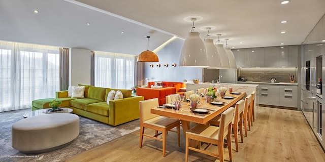 interior space featuring backsplash, light hardwood / wood-style floors, white cabinetry, and hanging light fixtures