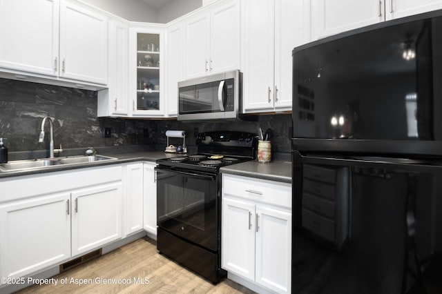 kitchen with decorative backsplash, sink, black appliances, light hardwood / wood-style flooring, and white cabinets