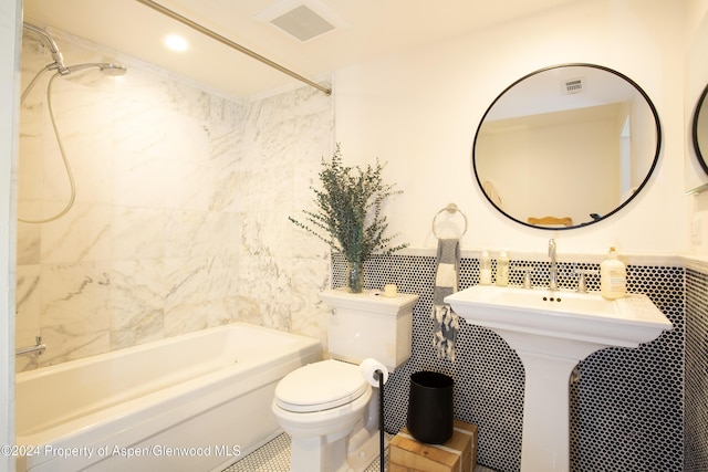 bathroom featuring toilet, tile walls, and tiled shower / bath